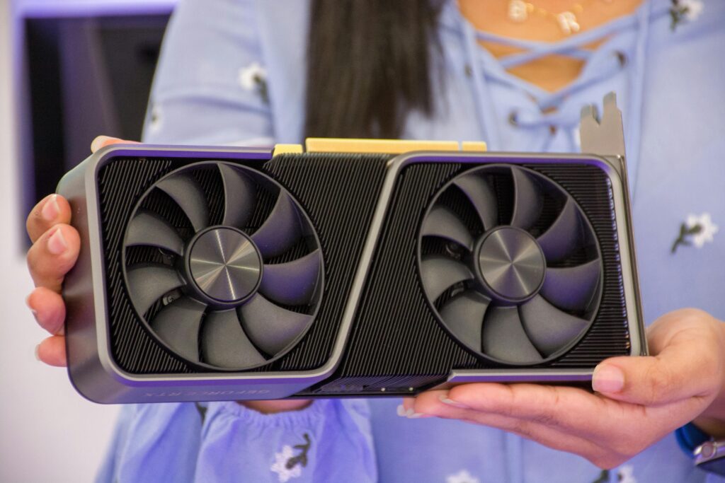 Detailed shot of hands holding a modern graphics card indoors.